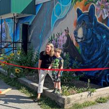 Grade 2 student Nolan Webb cut the ribbon for Rosemont's mural celebration. A grade 2 boy helps a female principal cut a ribbon in front of an elementary school